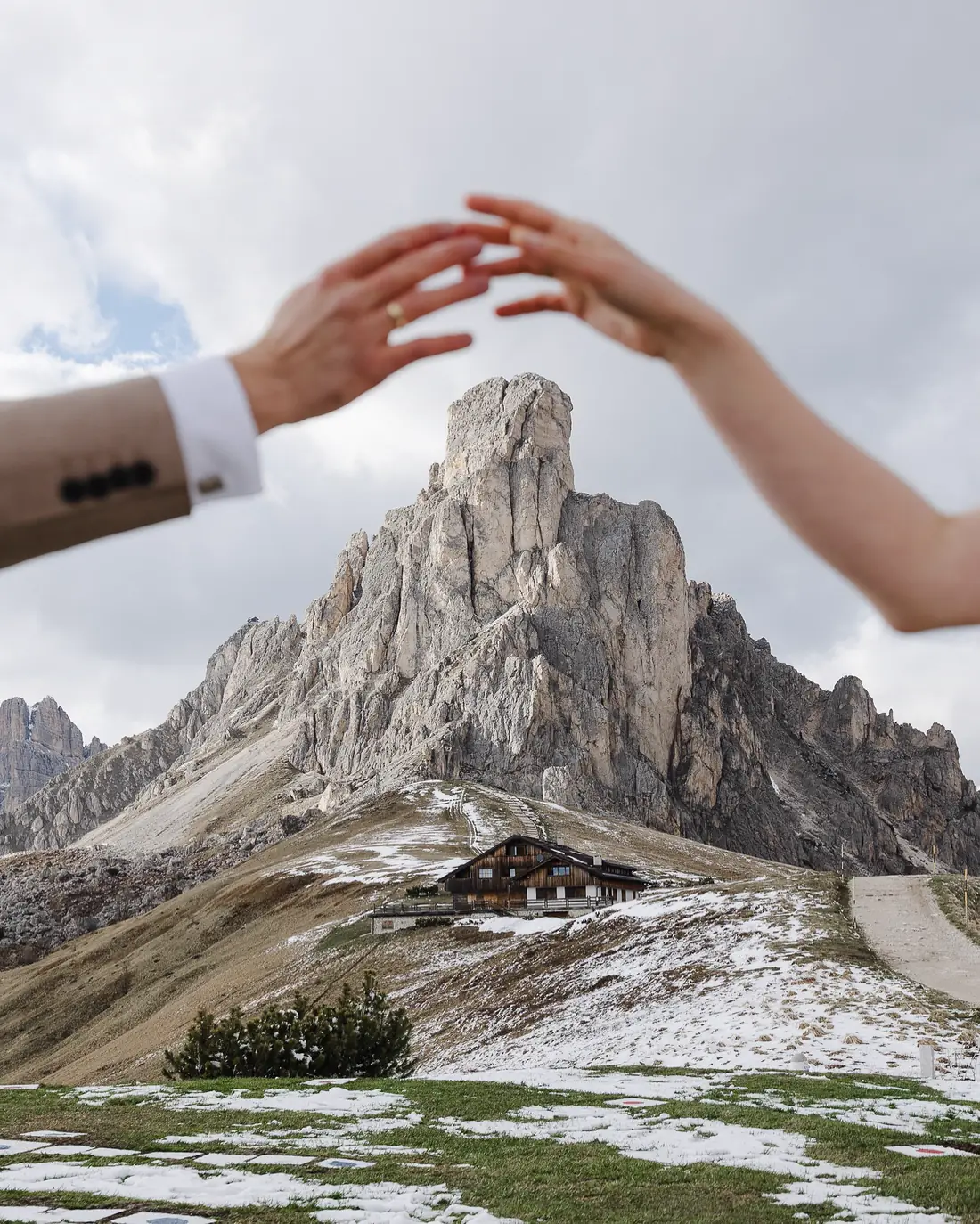 Dłonie Pary Młodej na tle górskiego szczytu w Dolomitach